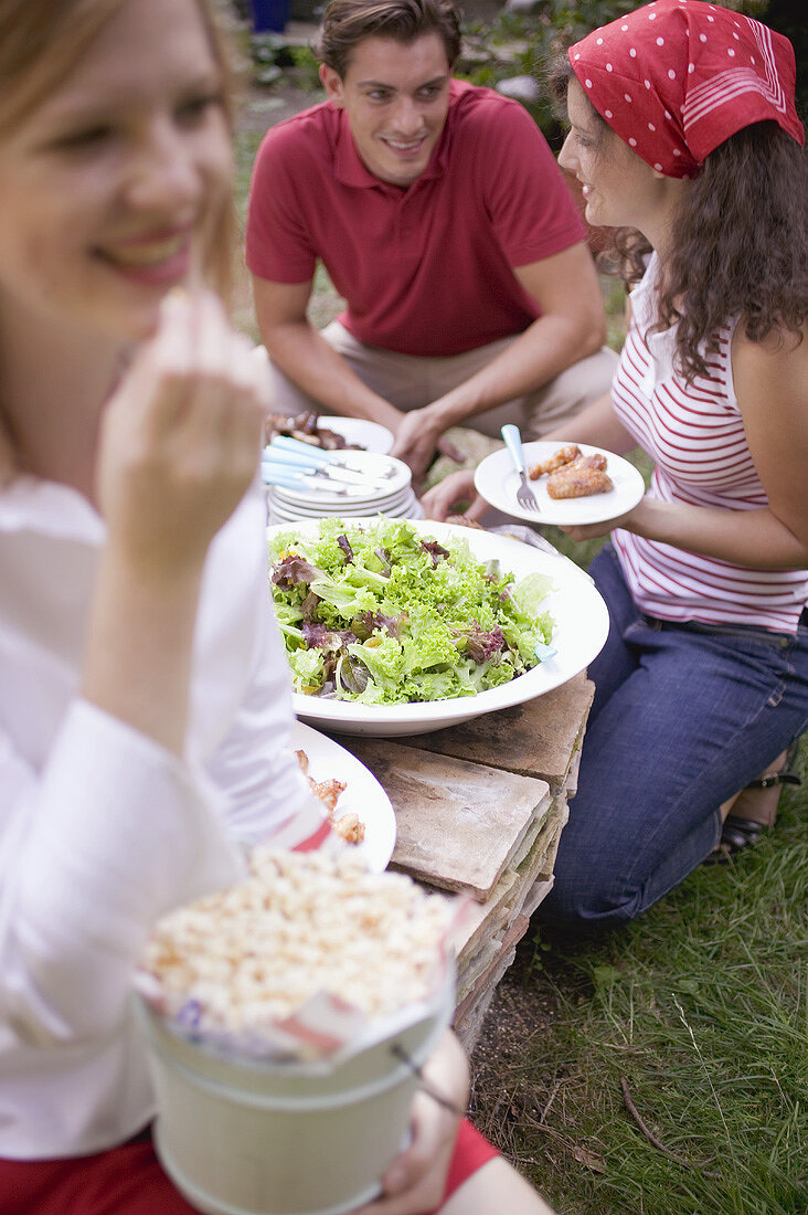 Young people with popcorn and salad at a barbecue