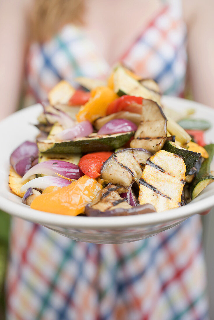 Woman holding a plate of grilled vegetables