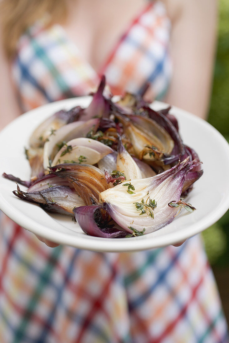 Woman holding a plate of grilled red onions