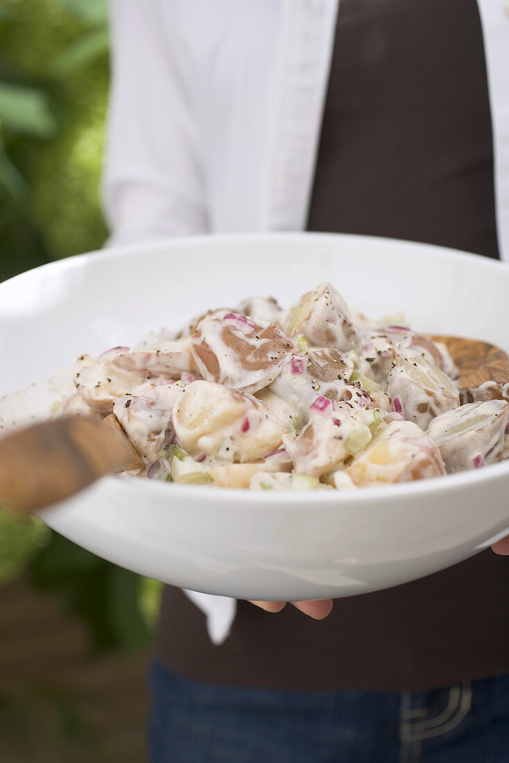 Person holding a dish of potato salad