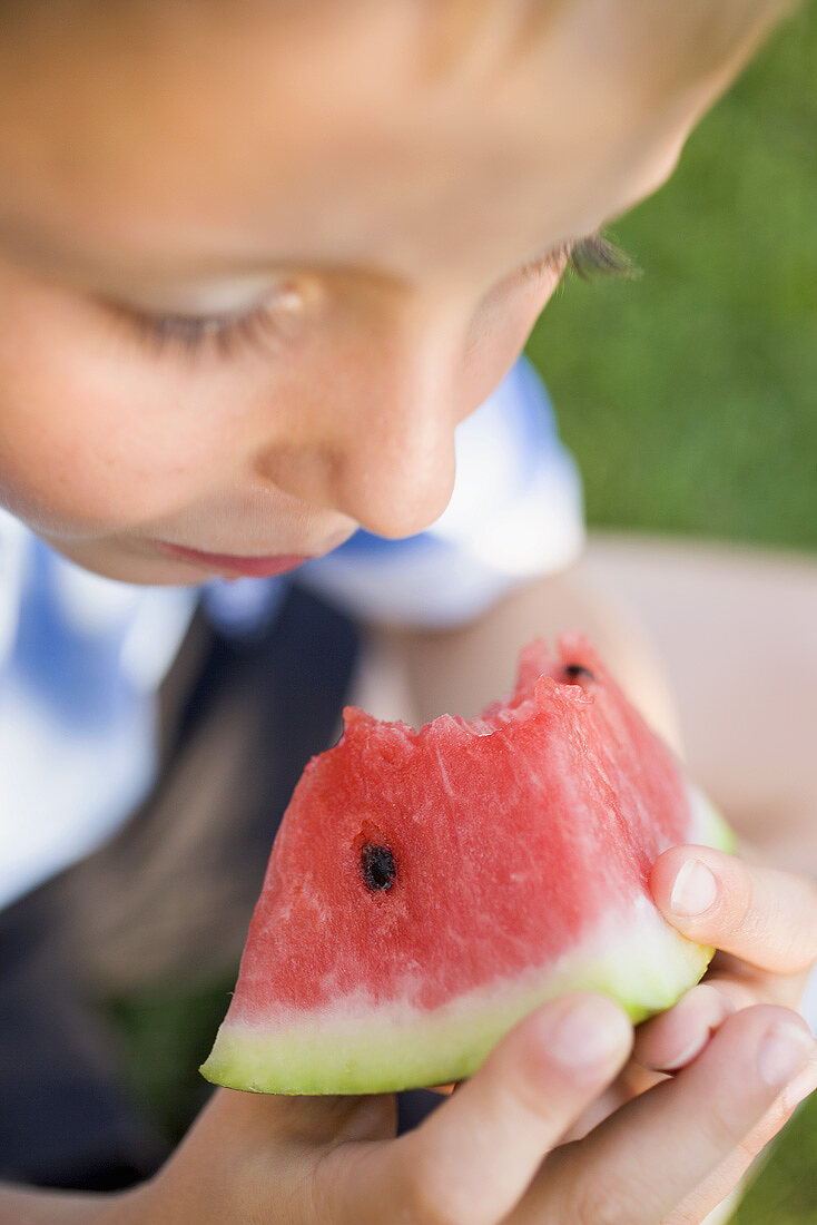 Kleiner Junge isst Stück Wassermelone