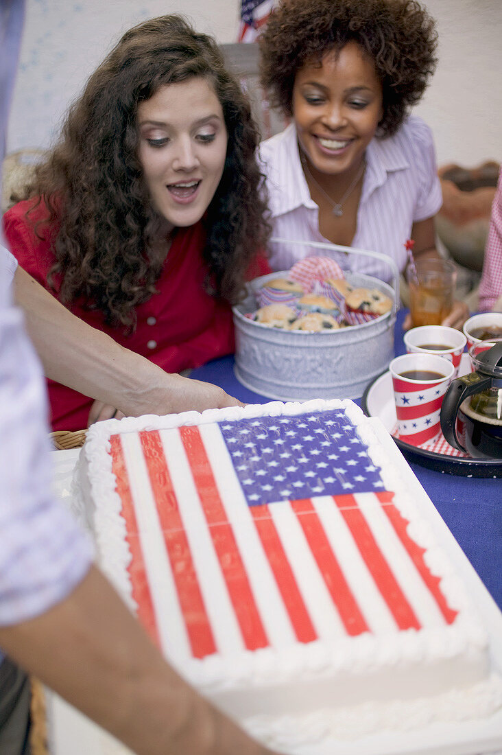 Zwei Frauen blicken freudig auf Torte zum 4th of July (USA)