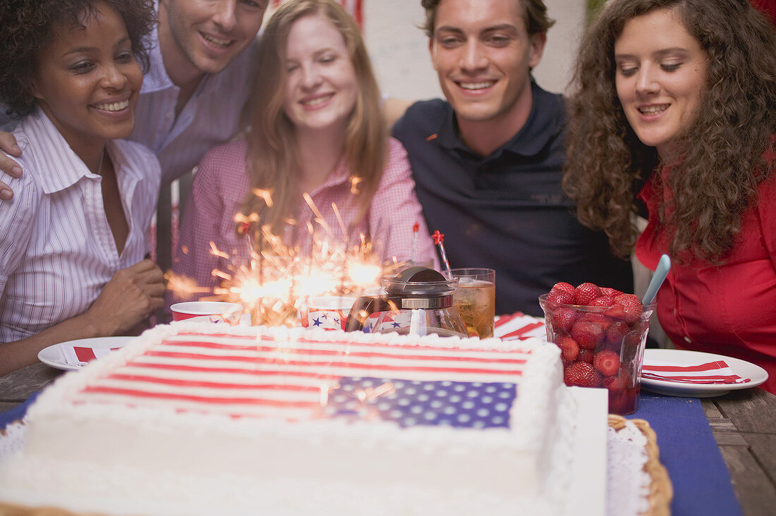 Junge Leute hinter Torte mit Wunderkerzen (4th of July, USA)