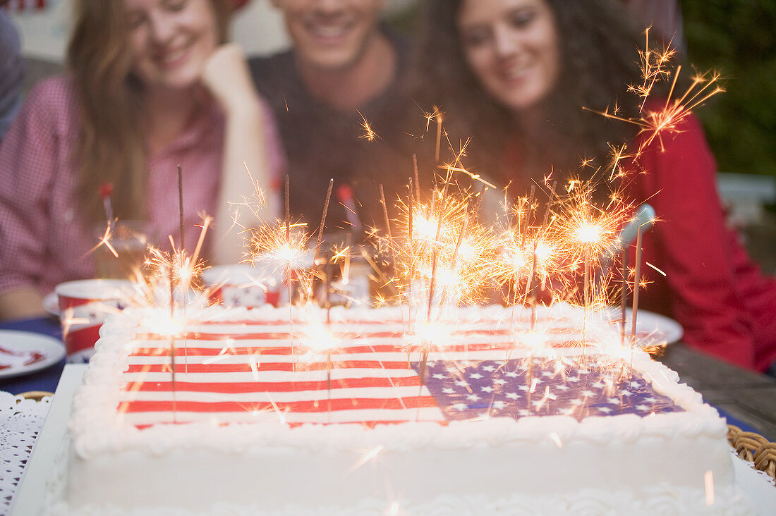Junge Leute hinter Torte mit Wunderkerzen (4th of July, USA)