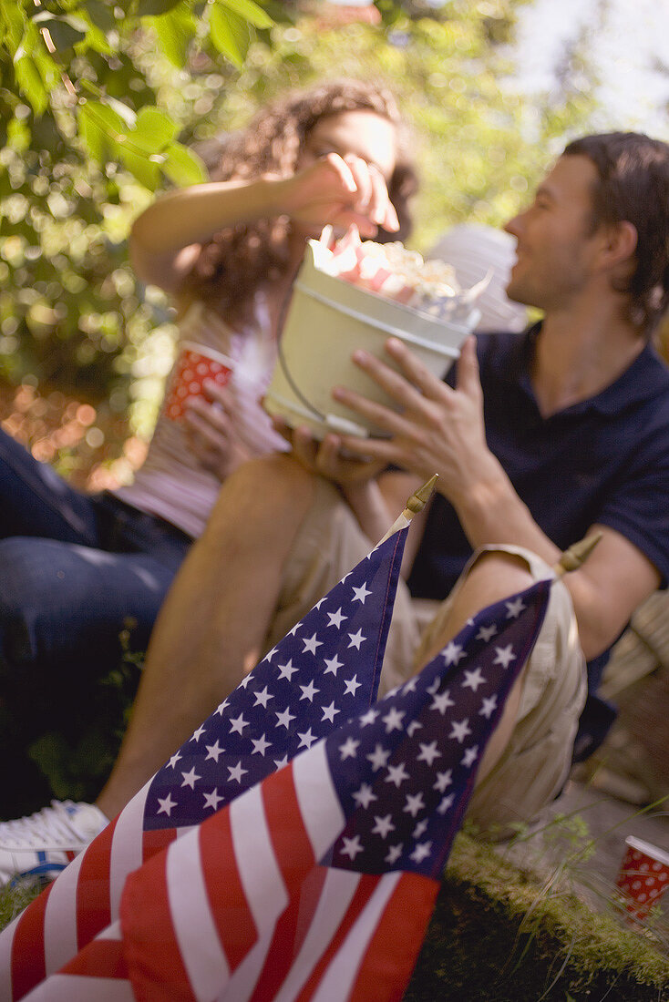 Couple with popcorn in wooden bucket on the 4th of July (USA)