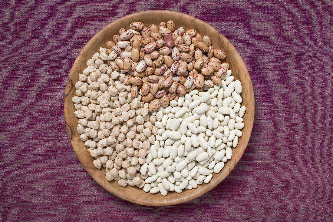Borlotti beans, white beans and chick-peas in wooden dish