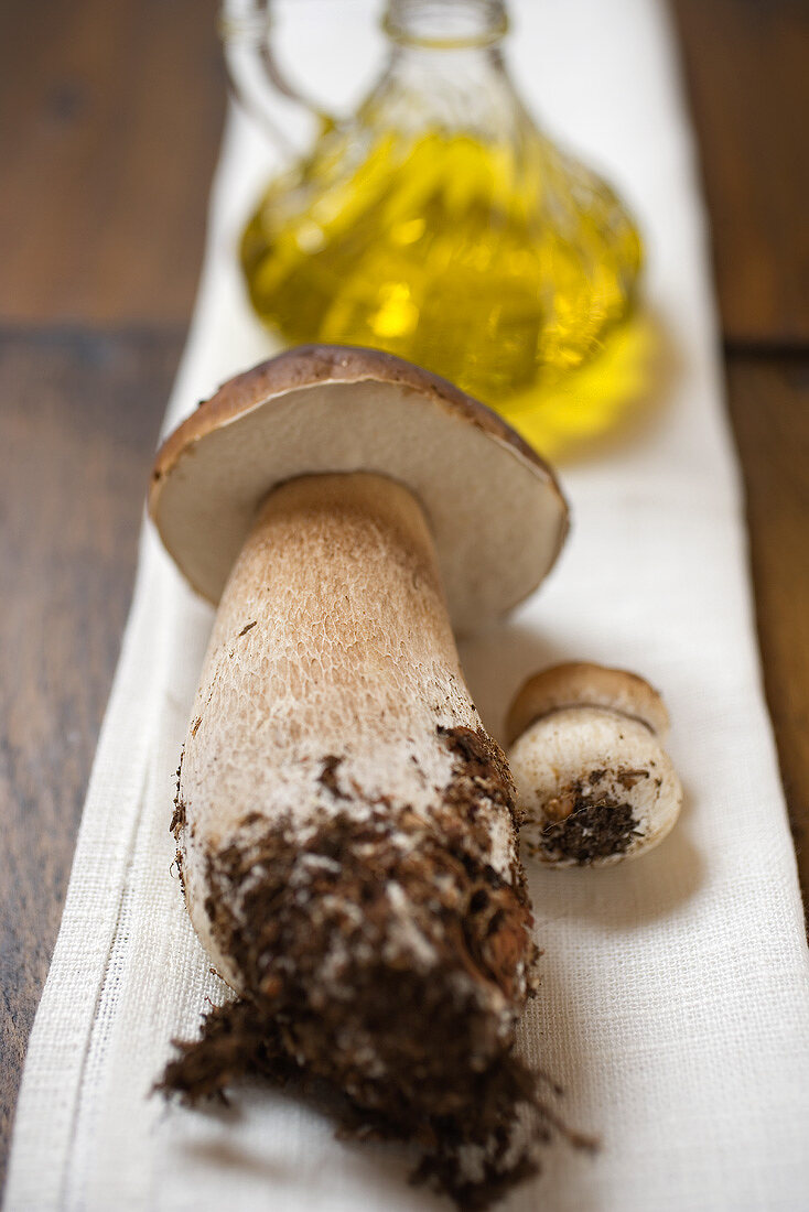 Ceps in front of a carafe of olive oil on linen cloth