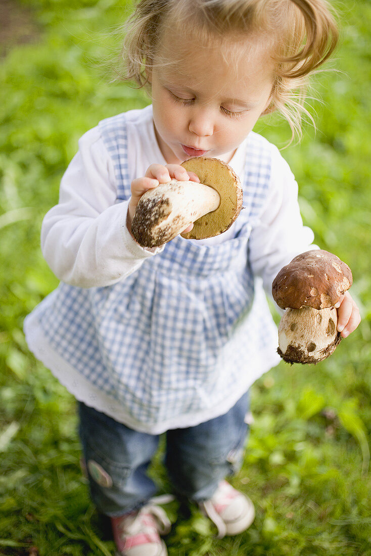 Small girl holding two fresh ceps