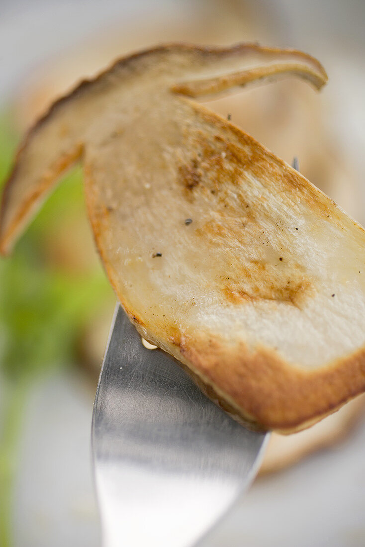 Gebratene Steinpilzscheibe auf Gabel (Close Up)