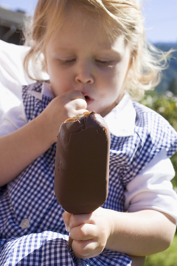 Mother holding small girl with ice cream on stick