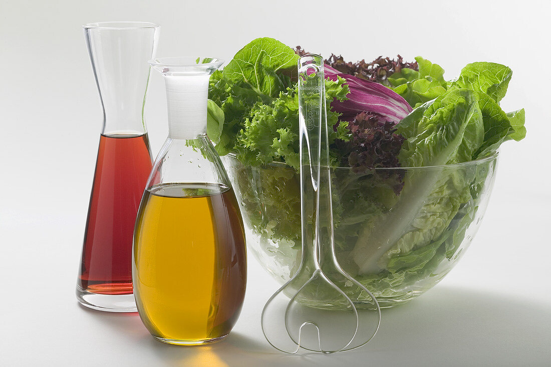 Oil & vinegar in carafes beside salad bowl, salad servers