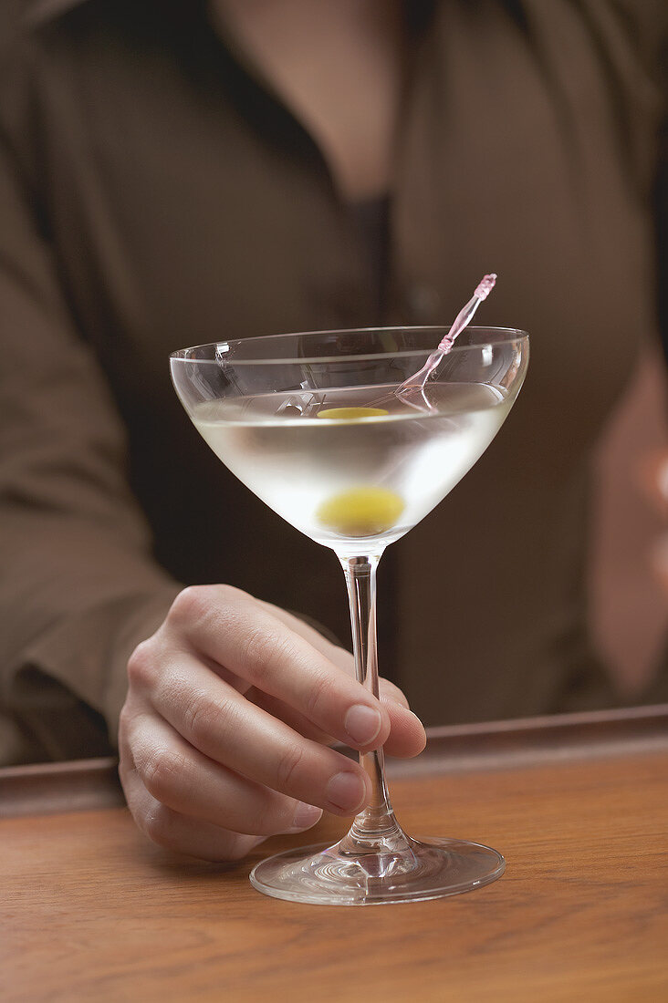 Frau hält Glas Martini mit Olive