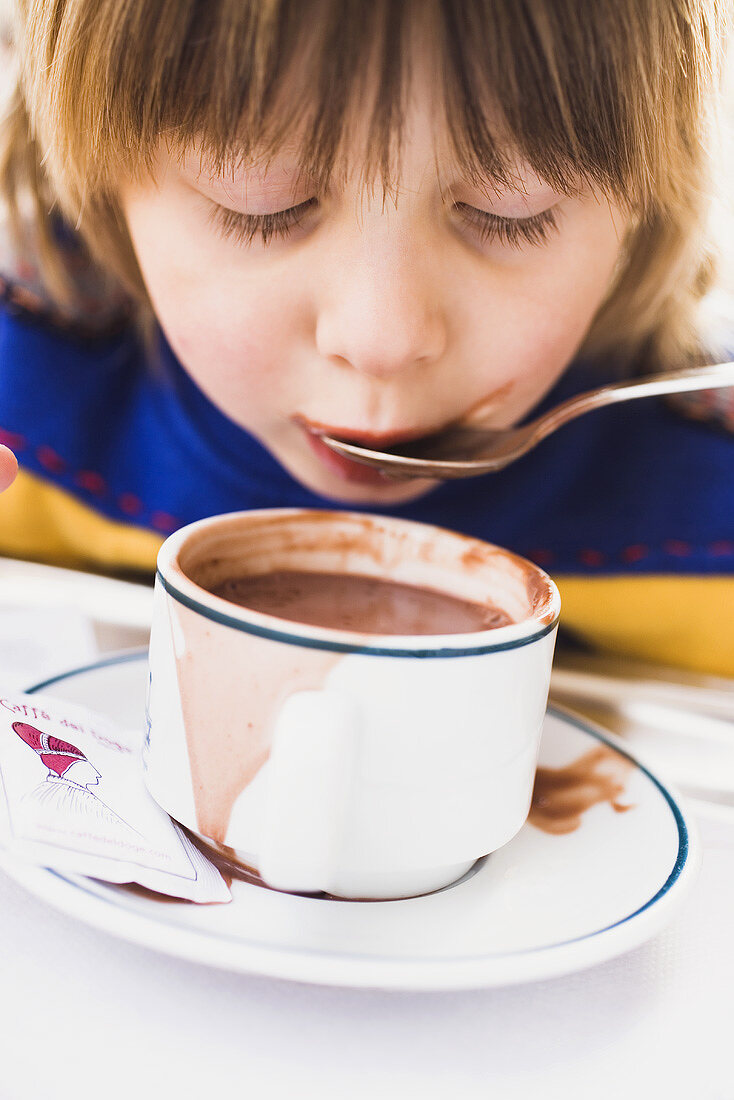 Child slurping cocoa from a spoon