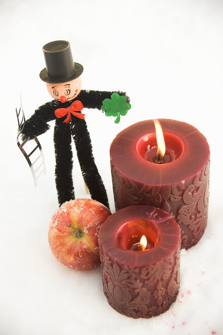 Chimney sweep, apple and red candles in snow