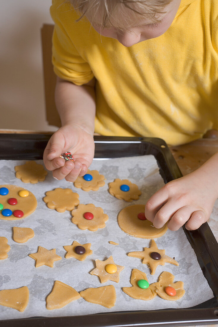 Child decorating biscuits with coloured chocolate beans