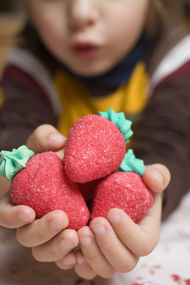 Child's hands holding marzipan strawberries