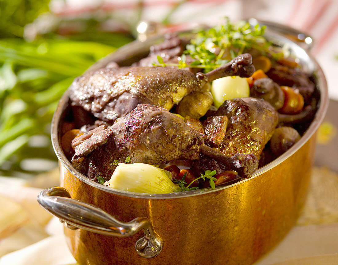 Braised duck legs with vegetables in a copper pot