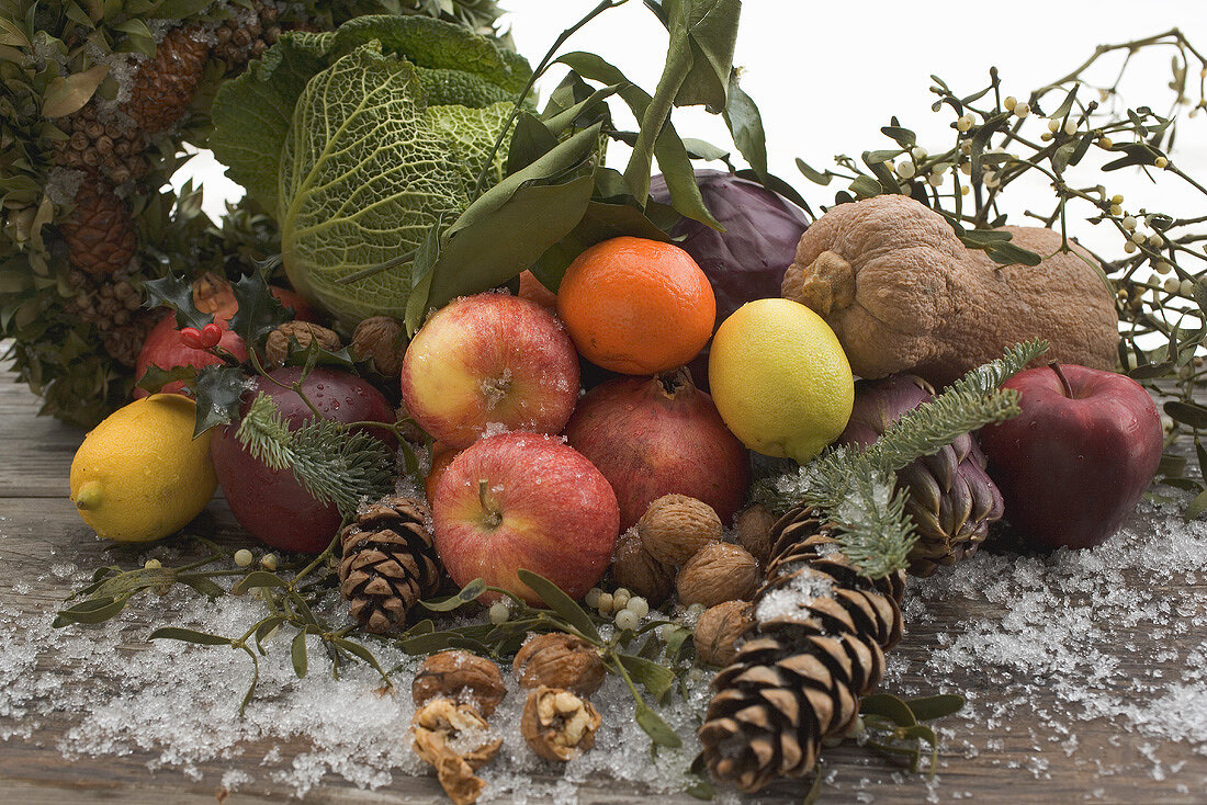 Obst, Gemüse, Nüsse, Tannenzapfen auf Holztisch im Freien