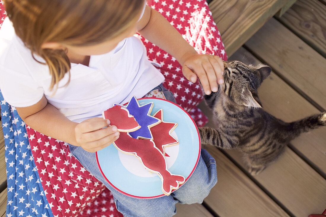 Kleines Mädchen mit angebissenem Plätzchen und Katze (USA)