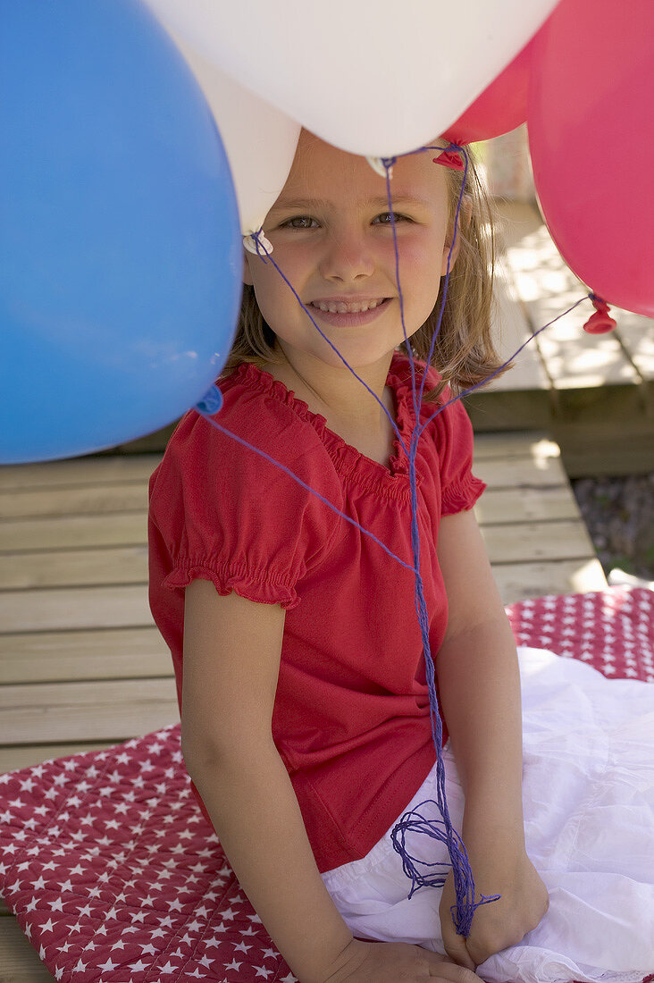 Kleines Mädchen hält Luftballons im Garten am 4th of July