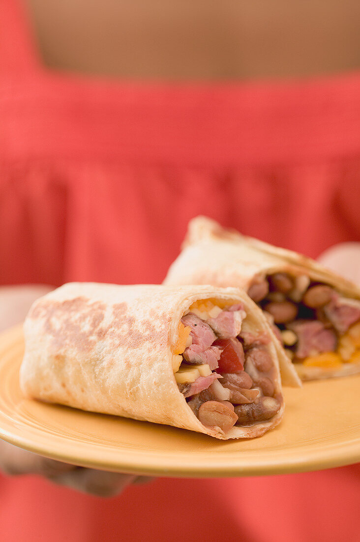 Woman holding two wraps on a plate