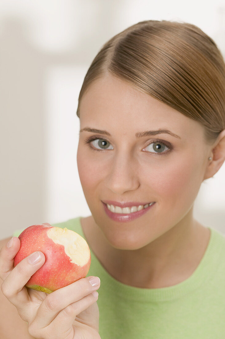 Woman holding a red apple with bites taken
