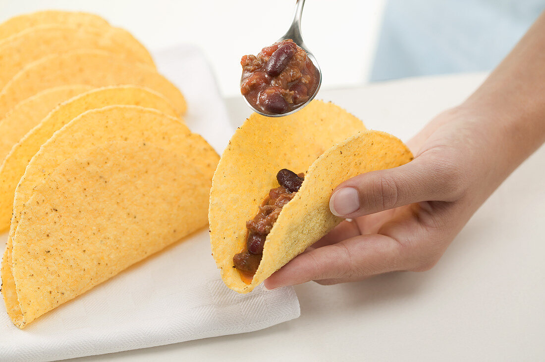 Filling tacos with chili con carne