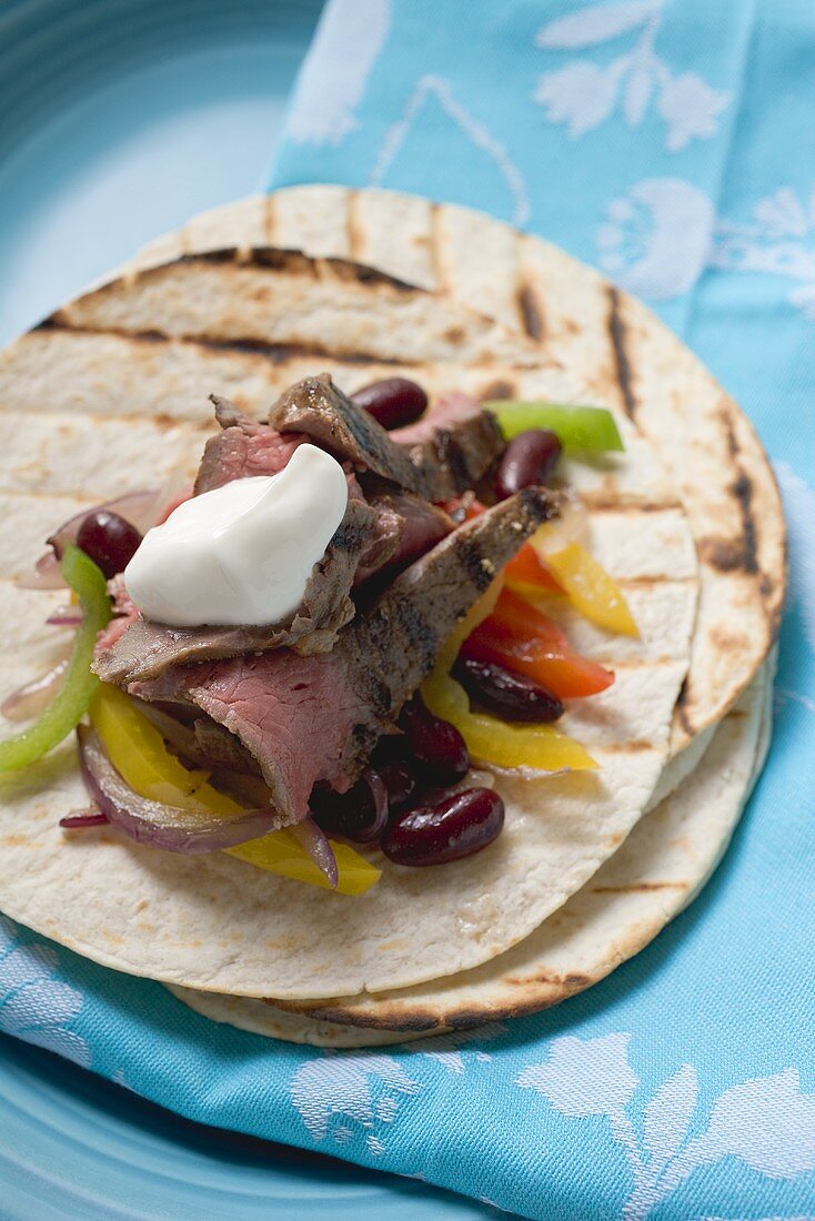 Fajita with beef, beans, peppers and sour cream