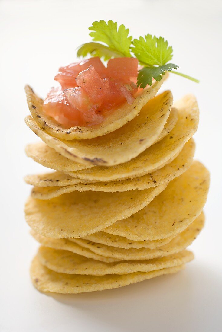 Tortilla chips, stacked, with tomato salsa and coriander