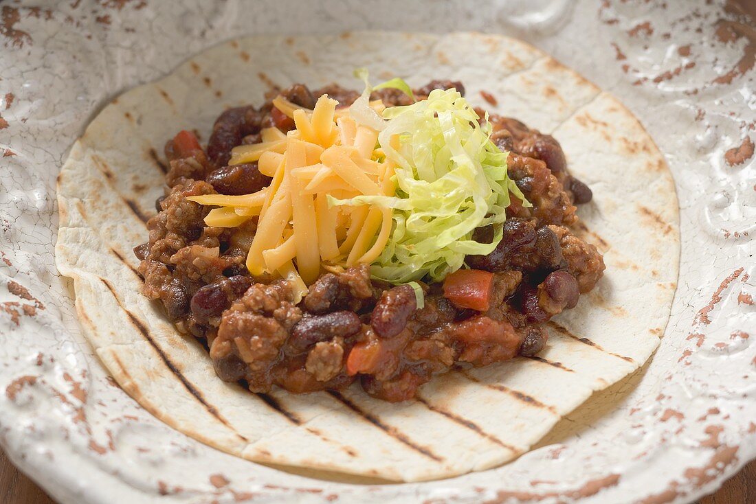 Mince and bean filling with cheese on tortilla (close-up)