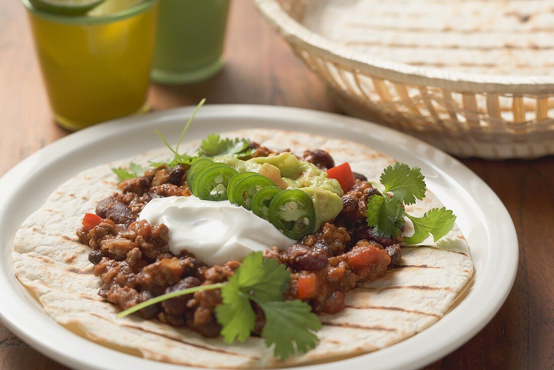 Mince and bean filling with sour cream on tortilla