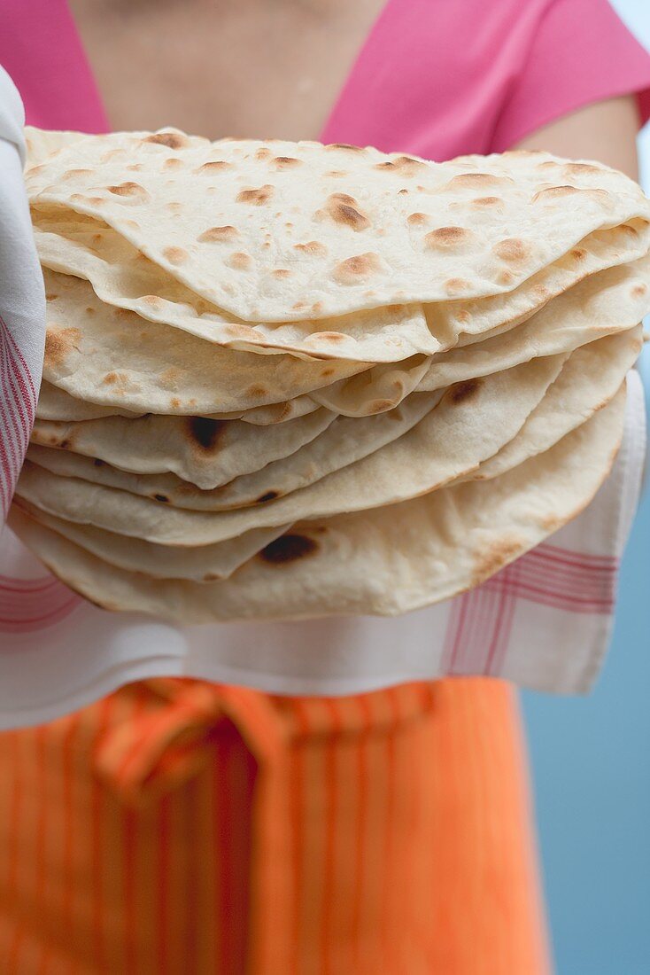 Frau hält frisch gebackene Tortillas auf Geschirrtuch