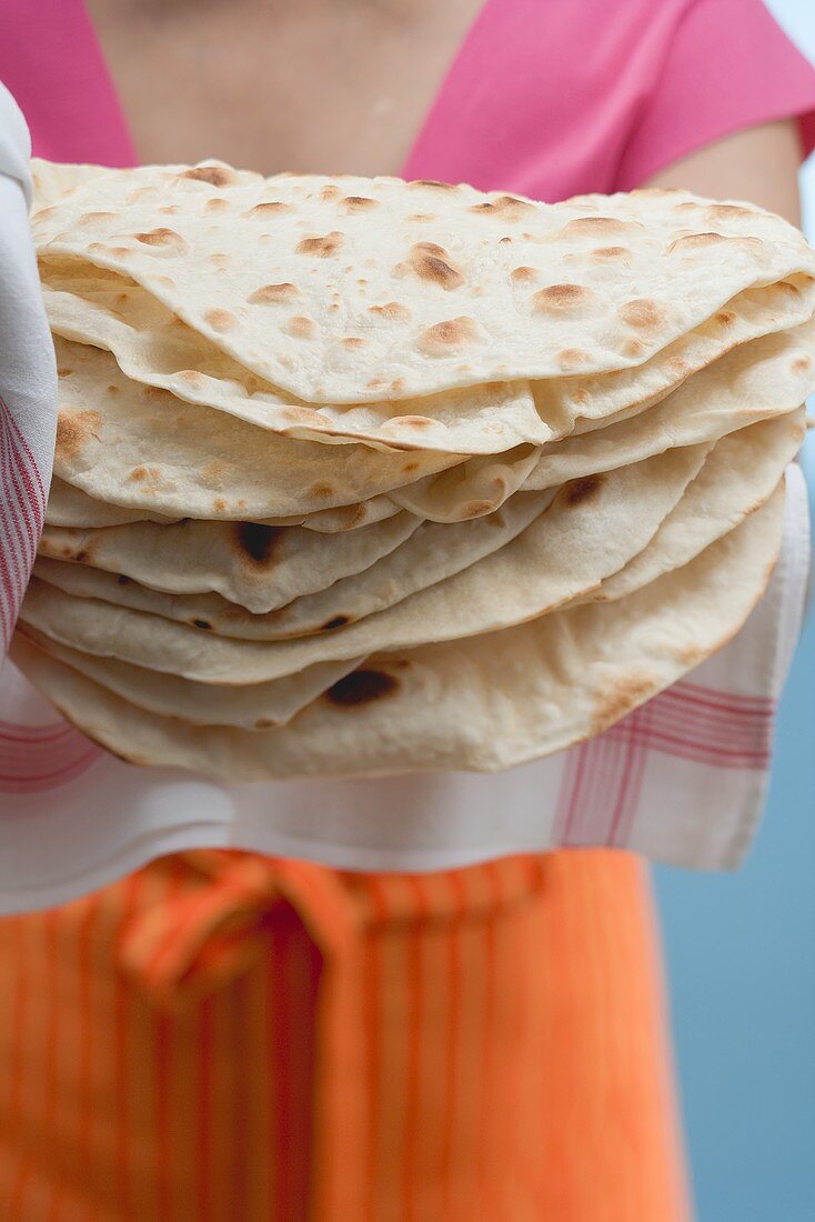 Woman holding freshly baked tortillas on tea towel