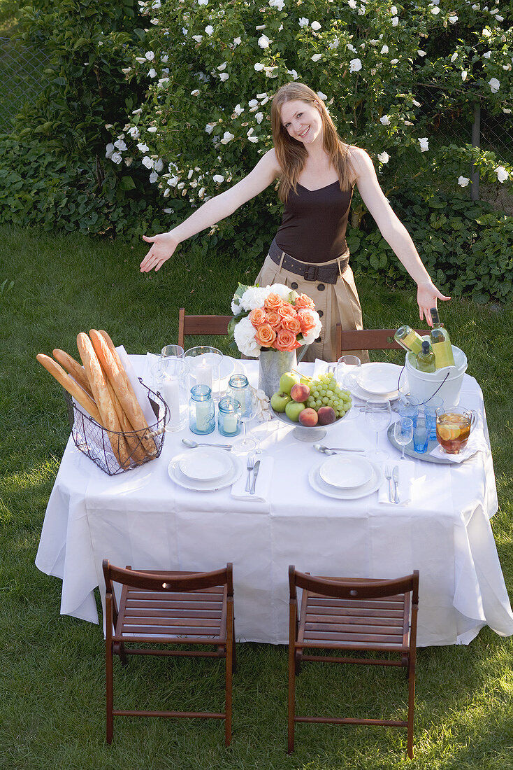 Frau präsentiert gedeckten Tisch im Garten