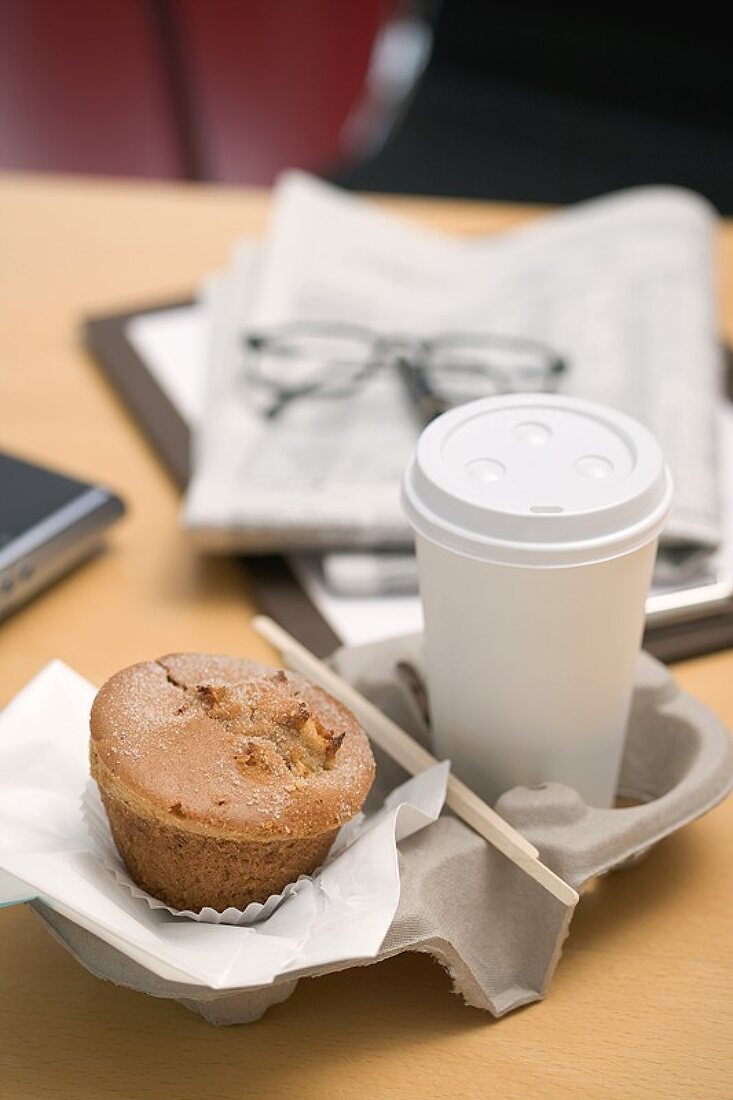 Muffin und Kaffeebecher im Büro