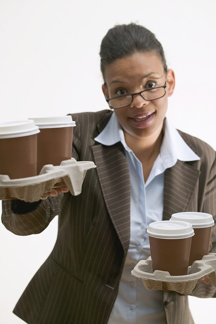 Businesswoman holding four cups of coffee