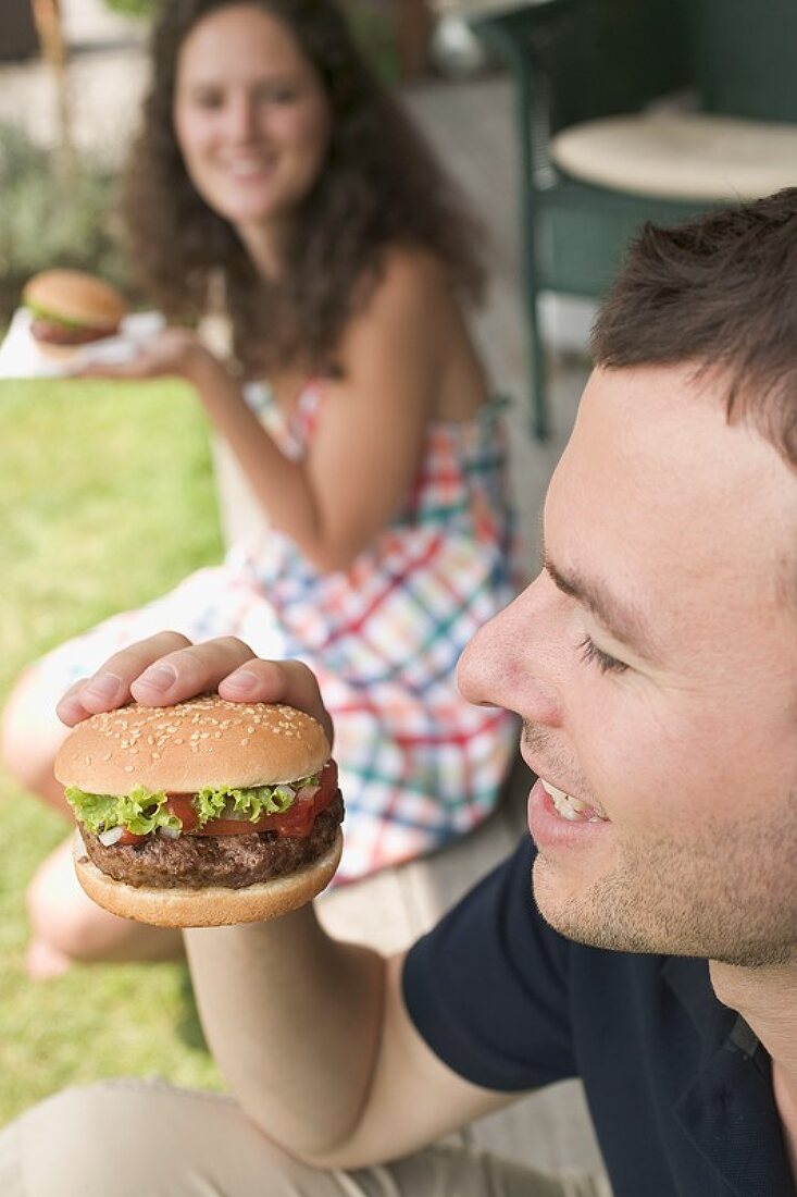 Paar isst Hamburger auf Terrasse