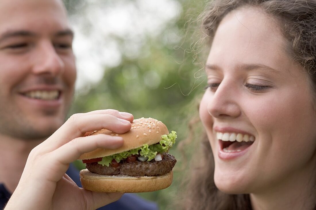 Man offering woman a bite of hamburger