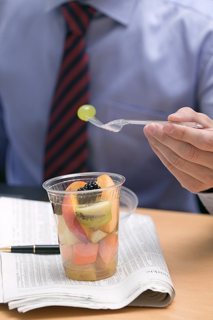 Geschäftsmann isst Fruchtsalat im Büro