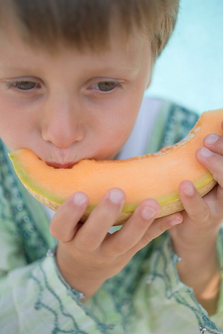 Kleiner Junge isst Melonenspalte
