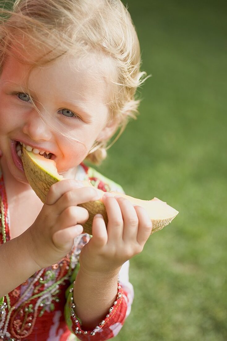 Kleines Mädchen isst Melonenspalte
