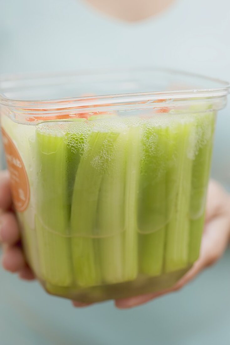 Woman holding plastic container of celery and carrots