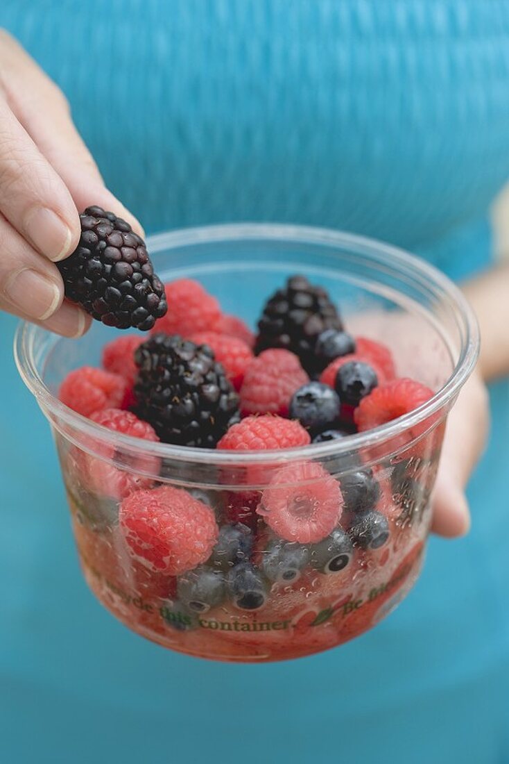 Woman holding plastic tub of fresh berries