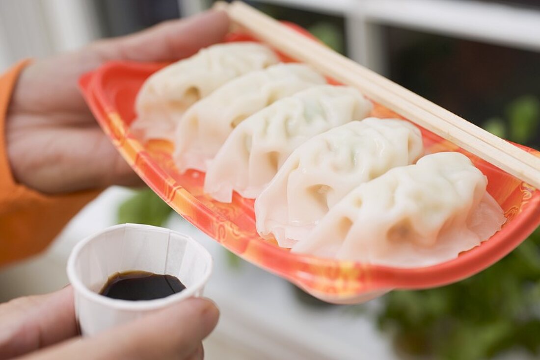 Woman holding wontons on plastic tray