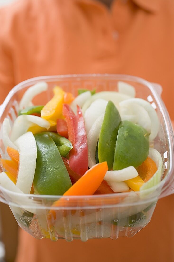 Woman holding plastic container of vegetables