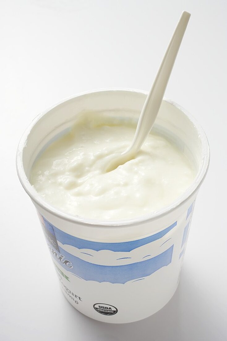 Natural yoghurt in pot with plastic spoon