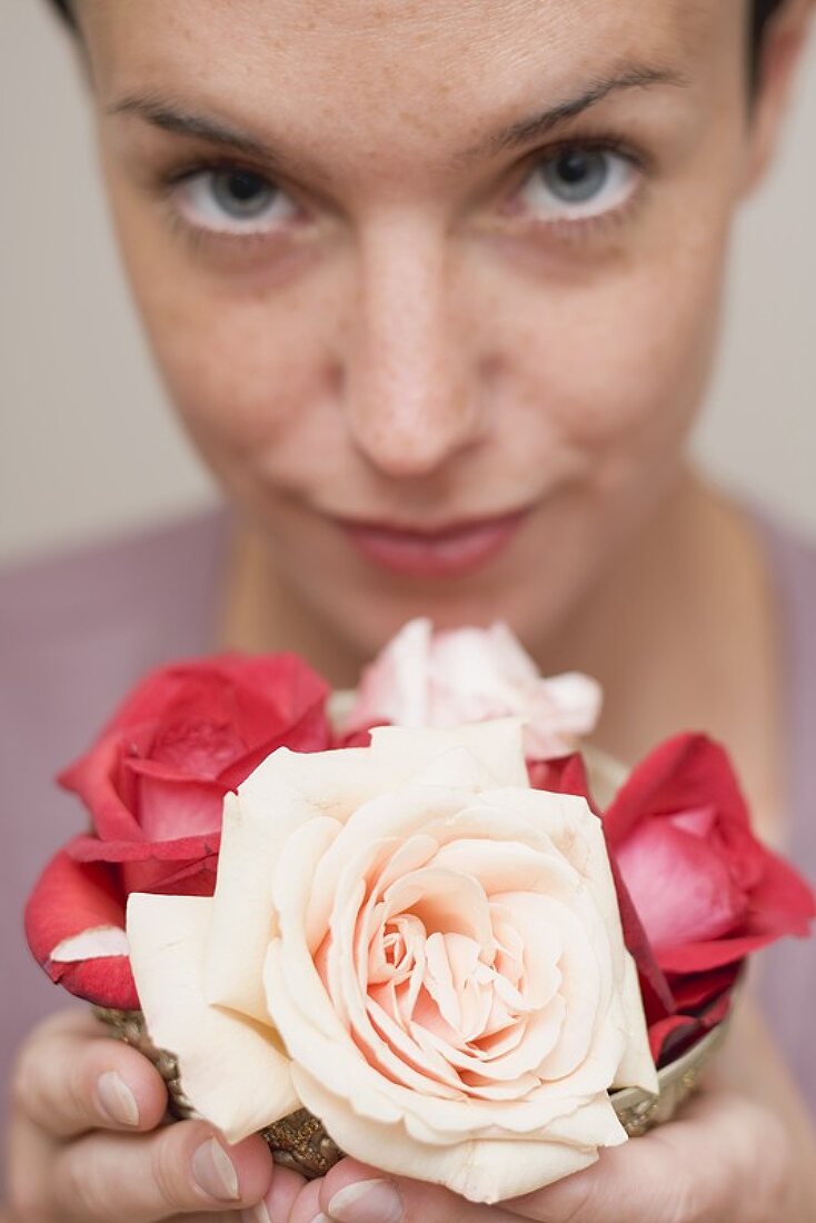 Frau hält Schale mit Rosenblüten