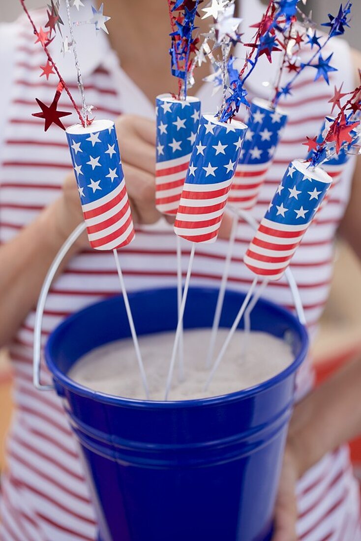 Woman holding bucket of sparklers in sand (4th of July, USA)