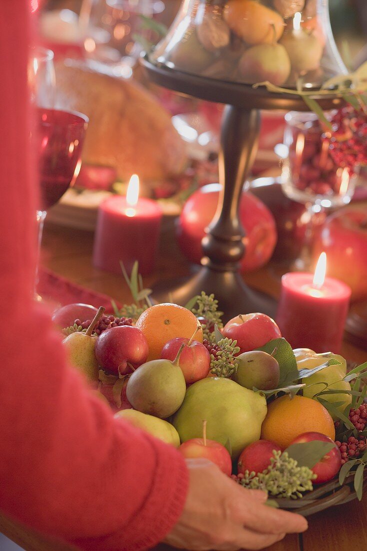 Frau stellt Obstschale auf weihnachtlich gedeckten Tisch