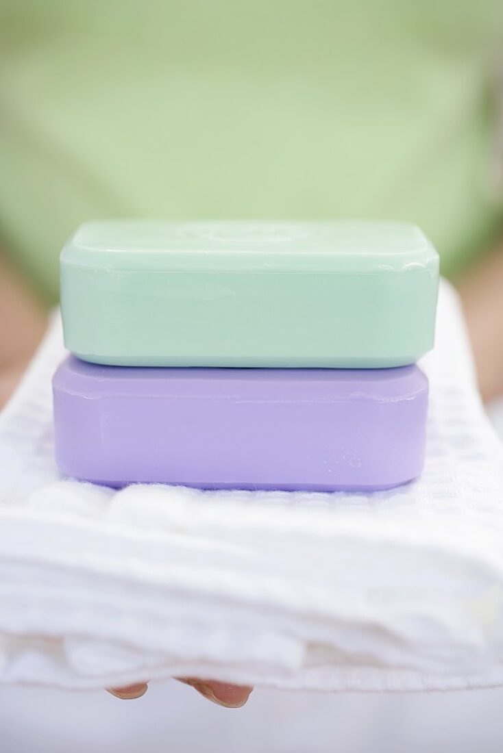 Woman holding two bars of soap on towel